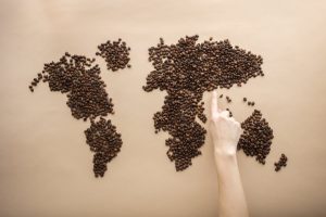 crop person pointing at world map of coffee beans