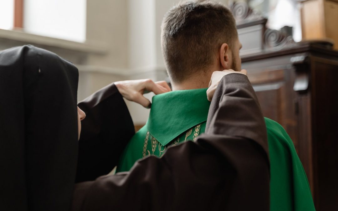 a priest getting help in fixing his stole